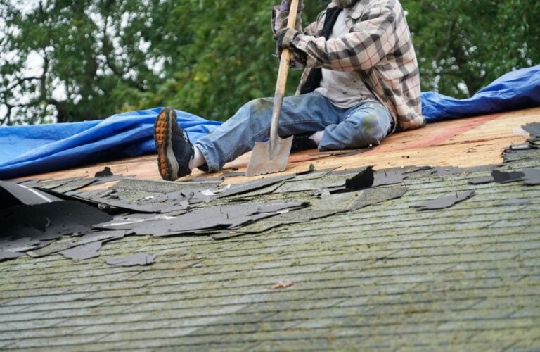 A roofer removing old shingles in preparation for roof replacement