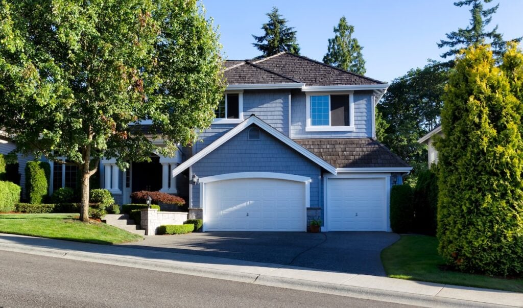 Curb view of a modern home with cedar shake roof during summer morning