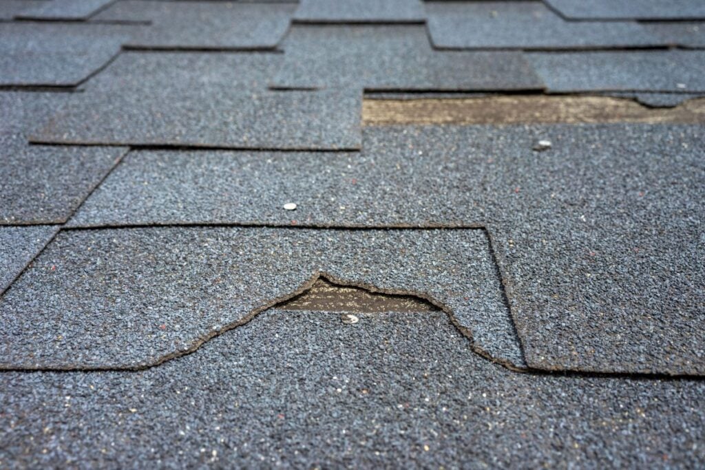 Close up view of bitumen shingles roof damage that needs repair