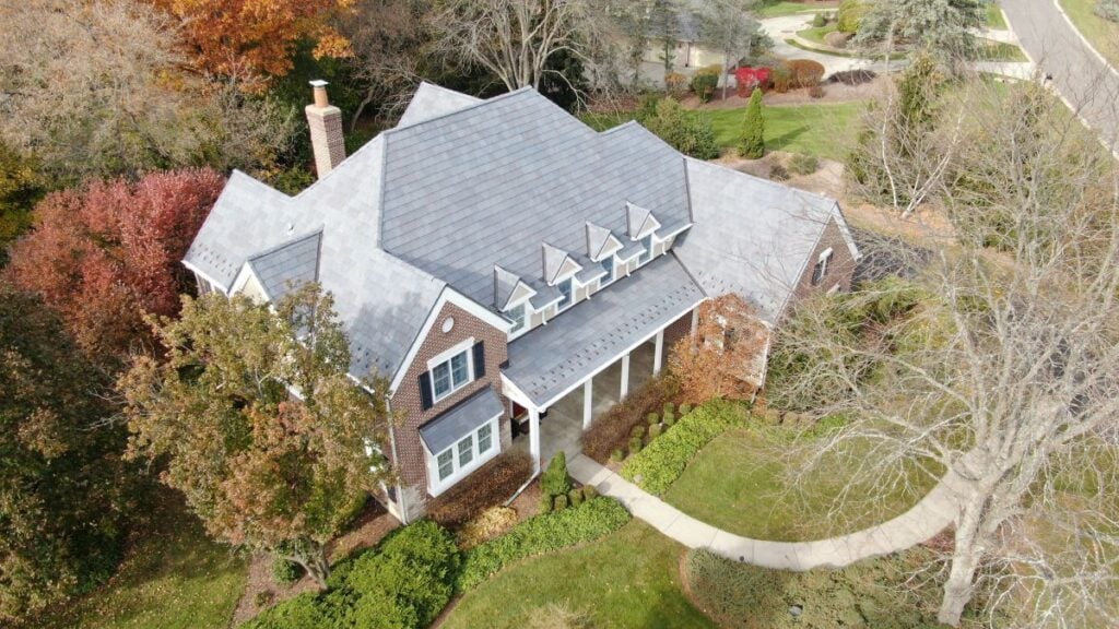 Aerial view of a house with a slate roof, surrounded by trees