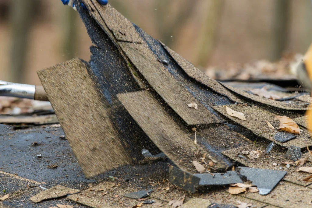 close up view of roof shingles being removed off of roofing system layer