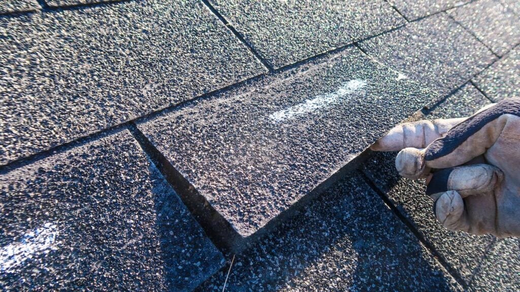 Residential roof inspection for an insurance claim due to storm damage. The asphalt shingles show signs of damage.